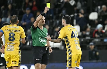 El árbitro Derlis Benítez exhibe la cartulina de amonestación al zaguero uruguayo, Agustín da Silveira, en el duelo entre Libertad y Sportivo Trinidense, disputado en el estadio La Huerta.