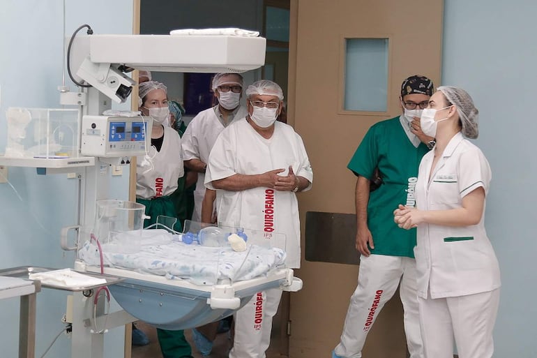 Isaías Fretes en el centro, con expresión de atención, acompañado de hombres y mujeres con mascarillas y batas blancas en entorno hospitalario.