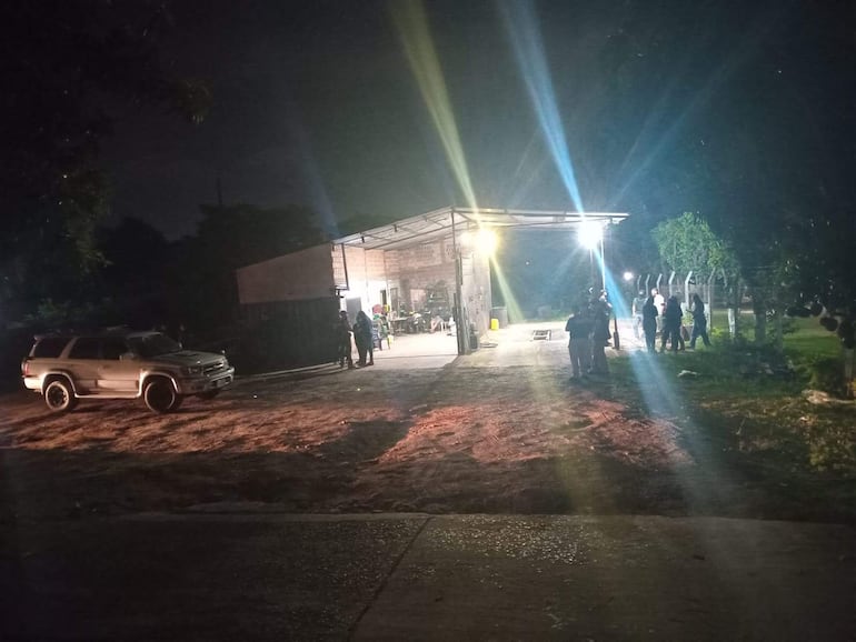 Grupo de seis personas conversando junto a un vehículo 4x4 en un entorno iluminado por luces artificiales, rodeados de vegetación.