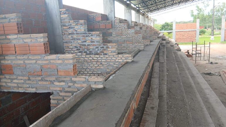 Estructura de graderías en obra, sin personas, con ladrillos anaranjados y grises bajo iluminación natural.