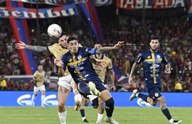 El zaguero de Sportivo Trinidense, Juan Ángel Vera despeja el balón ante la presión del delantero de Cerro Porteño, Juan Manuel Iturbe.