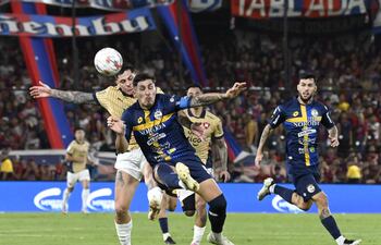 El zaguero de Sportivo Trinidense, Juan Ángel Vera despeja el balón ante la presión del delantero de Cerro Porteño, Juan Manuel Iturbe.
