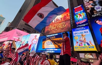 Aficionados paraguayos en camisetas rojas y blancas, con banderas en un ambiente festivo en Times Square.