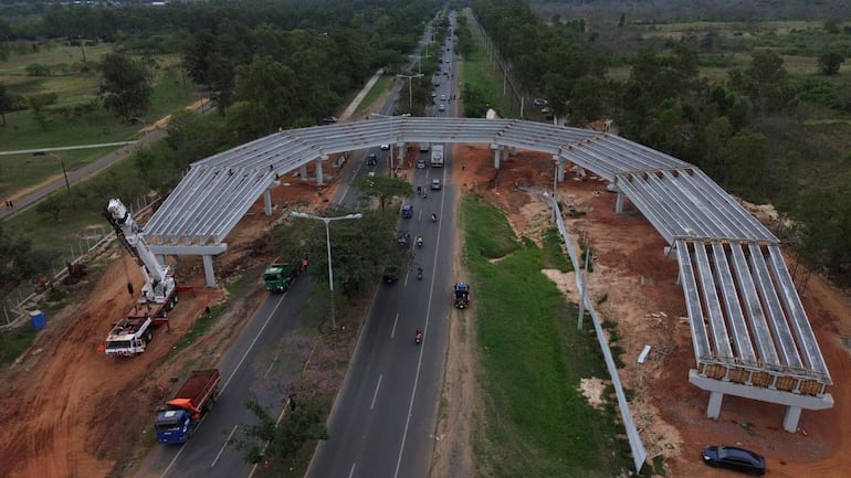 Obra en construcción de viaducto con grúas, vehículos y terrenos removidos en un área al aire libre.
