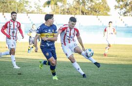 El lateral izquierdo de Sportivo Carapeguá, Tomás Mendoza despeja el esférico ante la presión del volante auriazul Cristhian Riveros. (Foto: @IntermediaAPF)