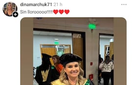 Dina Marchuk sonríe mientras sostiene su certificado de doctorado de la Universidad Columbia vestida con toga negra y birrete, en un ambiente festivo.