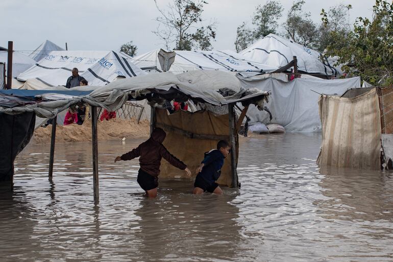 Niños cruzan una zona inundada de Jan Yunis, Gaza, luego de intensas lluvias en la Franja.