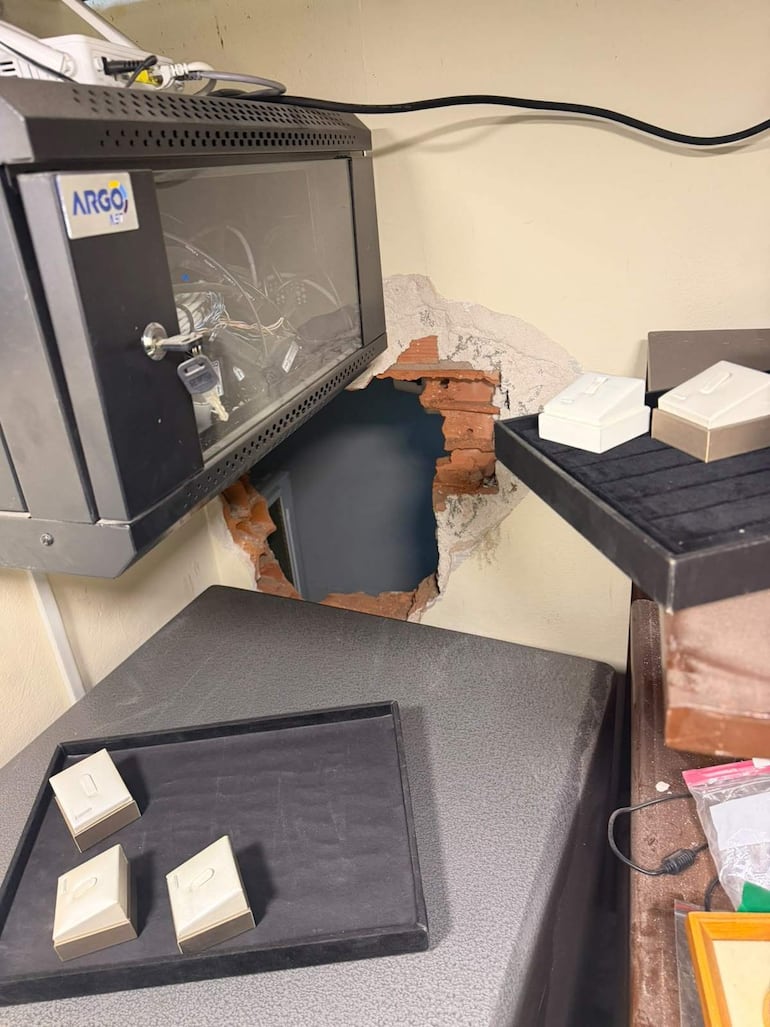 Ambiente interior de un cuarto desordenado con un agujero en la pared y cajas sobre una mesa.