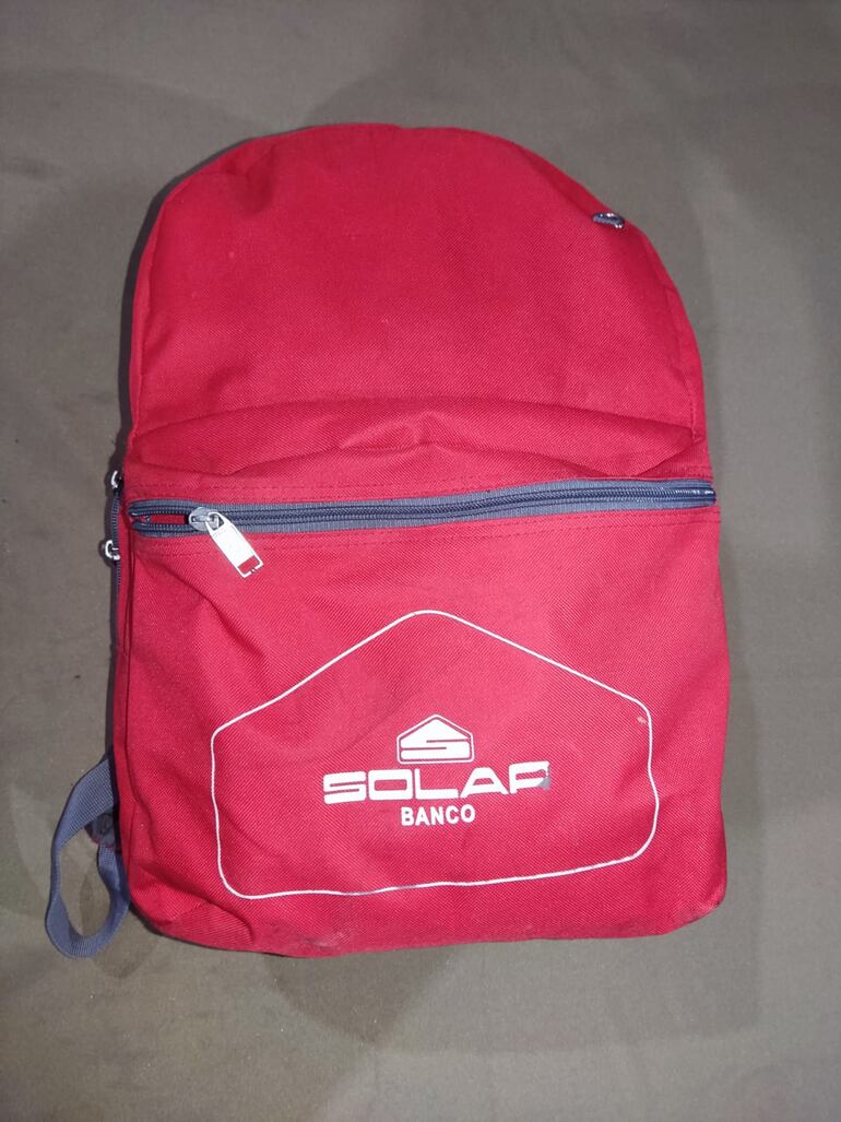 La mochila roja con los documentos que el maleante dejó en el auto de plataforma.