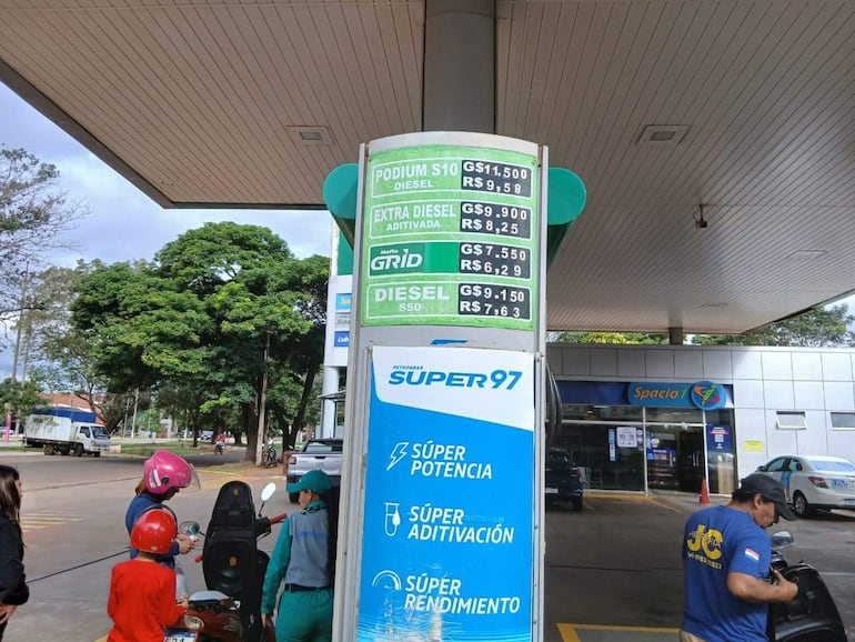 Clientes atendidos por hombre un playero en una estación de servicios.