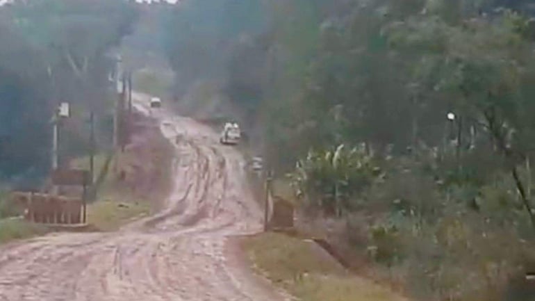 Ambulancia de bomberos azules atascada en barro, rodeada de vegetación en un camino rural.