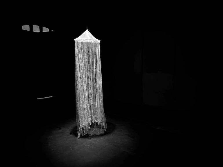 Estructura cónica iluminada en un espacio oscuro, centrada en un entorno artístico sin personas visibles.