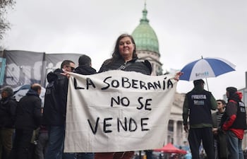 Una mujer sostiene un cartel en una manifestación contra un proyecto de ley impulsado por el Gobierno del ultraliberal Javier Milei que introduce cambios en los procesos de desalojo, expropiaciones y uso de tierras quemadas, este jueves en Buenos Aires.