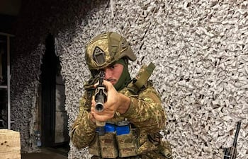 Derlis López, soldado en uniforme camuflado, agachado con arma larga en búnker, en la guera de Ucrania- Rusia