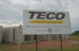 Cartel de obra de TECO constructora en el terreno donde permanecen abandonadas las estructuras de hormigó que deberían ser utilizadas para la abandonada obra.