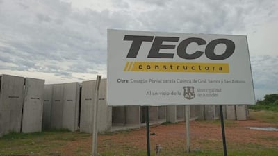 Cartel de obra de TECO constructora en el terreno donde permanecen abandonadas las estructuras de hormigó que deberían ser utilizadas para la abandonada obra.