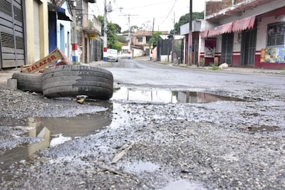 Calle desierta en Asunción con charcos de agua, neumáticos en el primer plano y edificios de ladrillo al fondo.