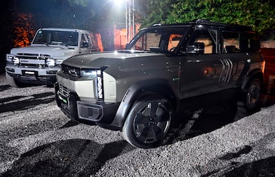 Presentación nocturna de dos SUVs en el evento de ICAURC, iluminados con luces artificiales sobre terreno de grava.