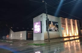 Establecimiento nocturno 'Venecia' iluminado, sin personas, en un entorno urbano con pavimento húmedo.