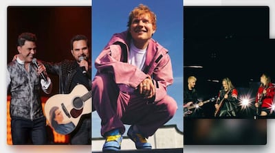 Dos hombres sonrientes, uno con guitarra y otro con micrófono, mientras tres músicos tocan enérgicamente en el escenario.