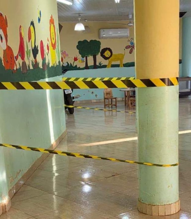 Interior del salón pediátrico del hospital, con mural decorativo y área cerrada por barrera de seguridad. Sin personas visibles.
