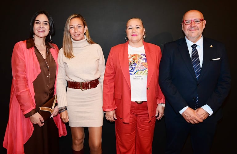 Mujeres sonrientes con atuendos coloridos y un hombre en traje oscuro en un evento en el Museo de Arte Sacro.