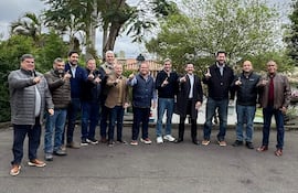 Mario Abdo Benítez y otros hombres se reúnen al aire libre, todos levantan un dedo índice, con expresiones felices y vestimenta casual.