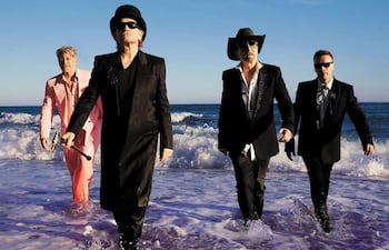 La banda U2 en un evento formal, luciendo trajes y abrigos mientras presentan su nuevo álbum.