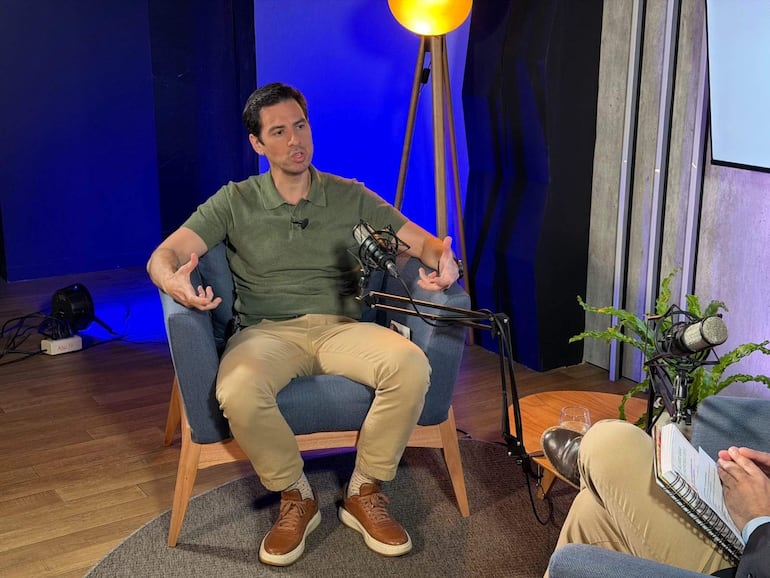 Alvaro Grau, vestido con camiseta verde oliva y pantalones beige, habla activamente mientras un asistente toma notas.