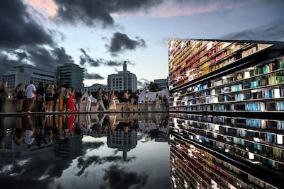 El público observa la exposición "LIBRARY OF US" de la artista británica Es Devlin, una estantería triangular giratoria de 15 metros de ancho que contiene 2.500 libros que han dado forma a la vida y la práctica de la artista, durante Art Basel 2025, en Miami Beach, Florida.