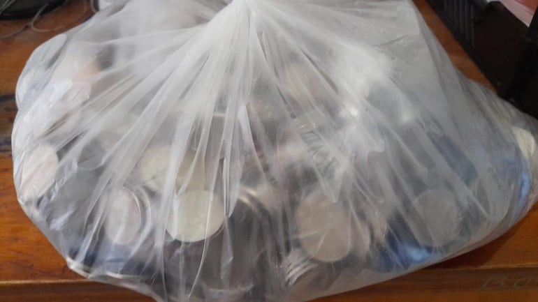 bolsa de hule cargada con monedas, que según los uniformados eran producto de la venta de las drogas.