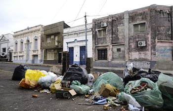 Entorno urbano con acumulación de basura y veredas rotas en Asunción, sin personas visibles en la escena.
