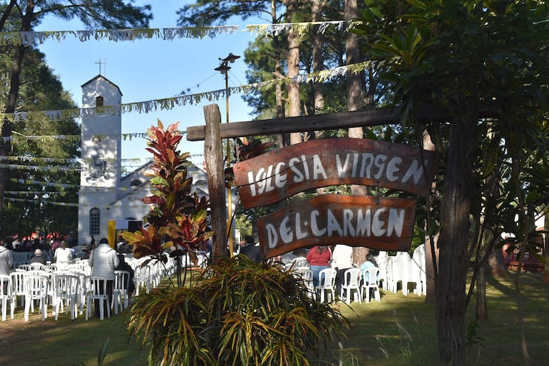 Vista del ambiente festivo exterior frente a la Iglesia Virgen del Carmen con plantas y sillas blancas dispuestas.