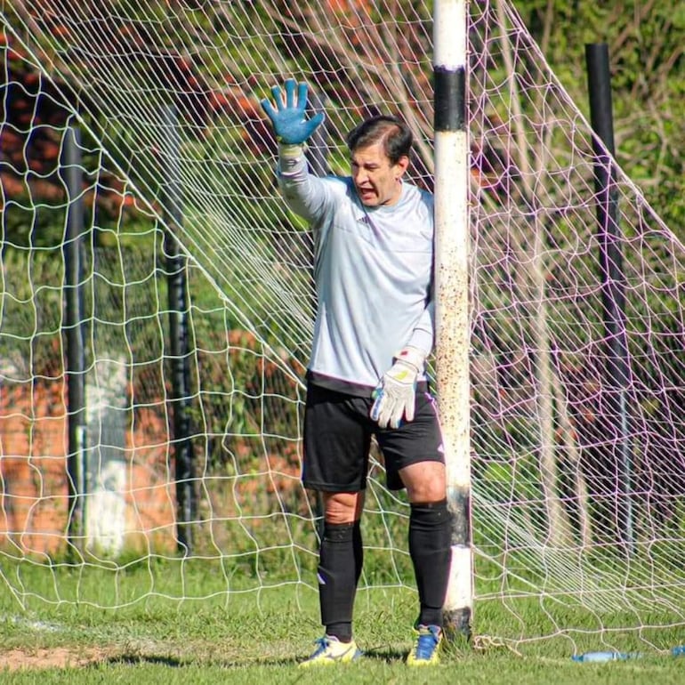 Silvio Beto Ovelar en uniforme gris claro y pantalones cortos oscuros, levantando la mano derecha en el área del portero.