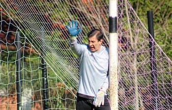 Silvio Beto Ovelar en uniforme gris claro y pantalones cortos oscuros, levantando la mano derecha en el área del portero.