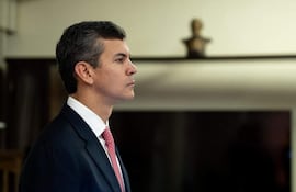 Santiago Peña Santi de perfil, con traje oscuro y corbata roja, muestra expresión de concentración en un ambiente con fondo neutro.