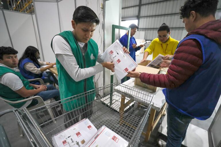 Personas alistan paquetes electorales del referéndum y de la consulta popular 2025 este lunes, en Quito (Ecuador).