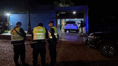 Cuatro agentes de la Policía Nacional conversan en un garaje nocturno, con un vehículo blanco estacionado detrás.