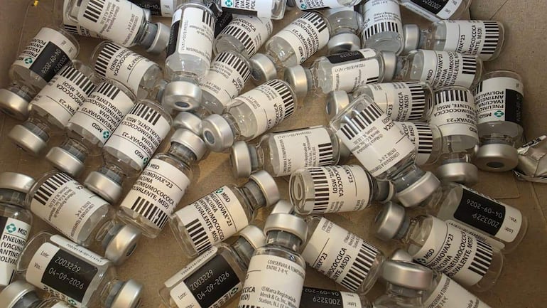 Ampollas de vacuna Pneumovax 23 de Merck en una superficie, sin personas visibles en un entorno de distribución.