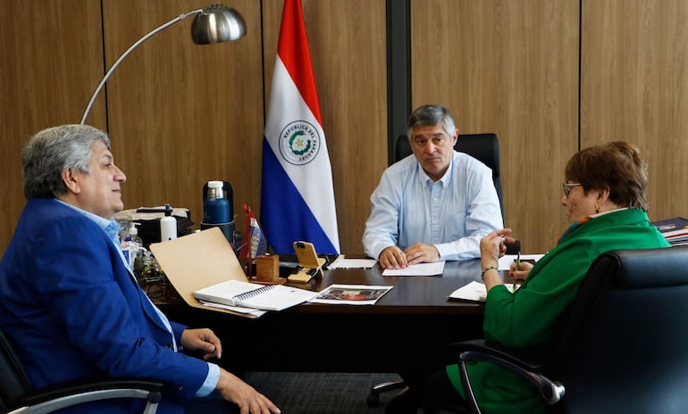 Luis Ramírez en traje azul escucha atentamente, mientras Blas Dubrez en camisa blanca habla y Peggy Martínez toma notas con camiseta verde.