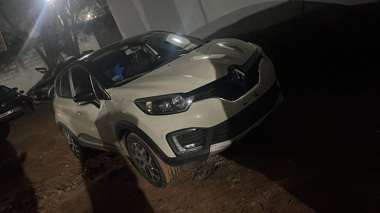 SUV Renault blanco estacionado en terreno de tierra, en un área de poca iluminación y sin personas presentes.