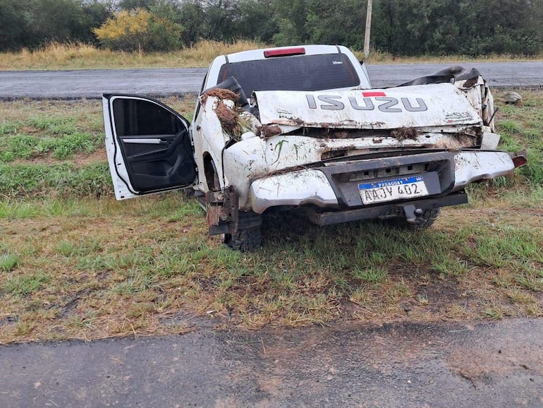 Camioneta Isuzu dañada estacionada en área verde con puerta del conductor abierta, sin personas visibles.