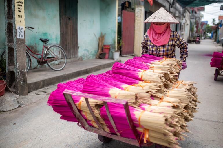 Un fabricante de incienso transporta manojos de varitas recién teñidas en Quang Phu Cau. El incienso está experimentando un auge mundial, no solo en los templos asiáticos, sino también en los estudios de yoga, de Buenos Aires a Berlín. A menudo se producen en masa. Pero en Vietnam, un pueblo entero se dedica a la fabricación artesanal.