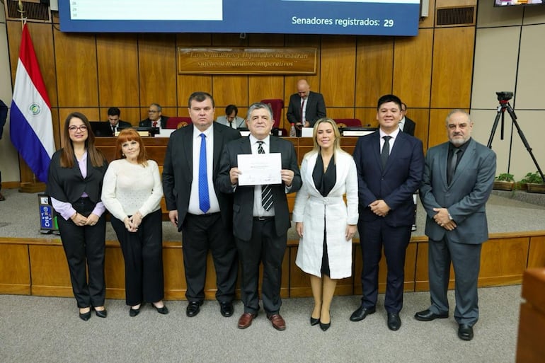 El compositor Carlos Cazal exhibe su certificado de reconocimiento junto a los integrantes del jurado.