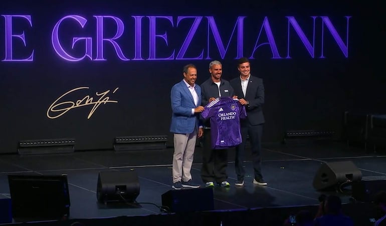 Captura de un video difundido por el equipo de la MLS Orlando City del futbolista francés Antoine Griezmann (c) posando con el dueño y presidente del Orlando City Mark Wilf (i) y el director deportivo Ricardo Moreira este martes, durante su presentación como nuevo jugador, en Orlando (FL, EE.UU.).