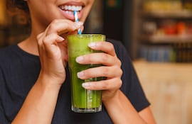 Mujer bebe un jugo verde.