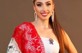 Natasha Reckziegel sonríe con blusa y falda blanca, coronada, envuelta en los colores de la bandera paraguaya.