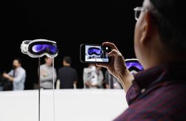 Un hombre toma fotografías de las gafas Apple Vision Pro durante la Conferencia de Desarrolladores de Apple en Cupertino, California (EE.UU.). Un anhelo desde hace años por fin se materializará tras el lanzamiento de Apple Vision Pro, un set de gafas y auriculares de realidad virtual (VR) y realidad aumentada (AR). Según Tim Cook, principal responsable de la empresa, es "un producto revolucionario" que los usuarios pueden controlar con sus propios ojos y manos sin la necesidad de ningún mando y que permite ver a otra persona cuando se acerca.