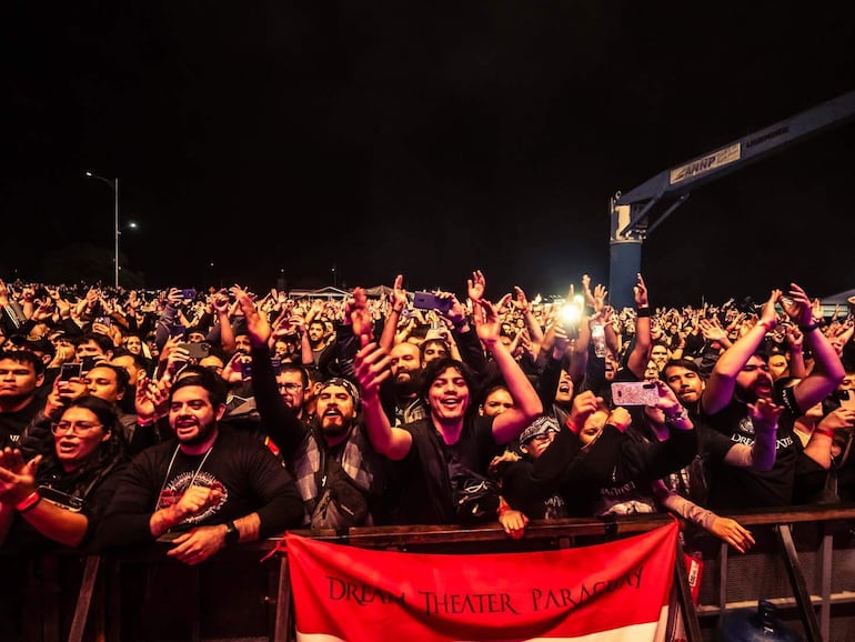 Público enérgico en concierto de Dream Theater, muchos levantan los brazos y graban con teléfonos móviles.