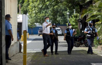 El secretario de la junta directiva del diario La Prensa, Juan Lorenzo Holmann (c), camina vigilado por agentes de policía en durante un operativo de allanamiento en la sede de dicha casa editorial en Managua (Nicaragua).